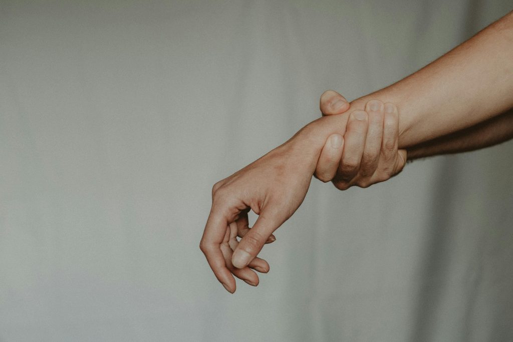 A close-up of two hands gently holding each other, symbolizing support and connection.