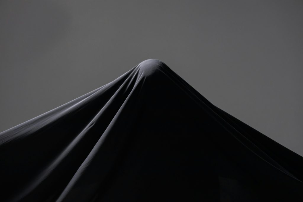 A draped black veil in soft studio lighting creating a mysterious silhouette.